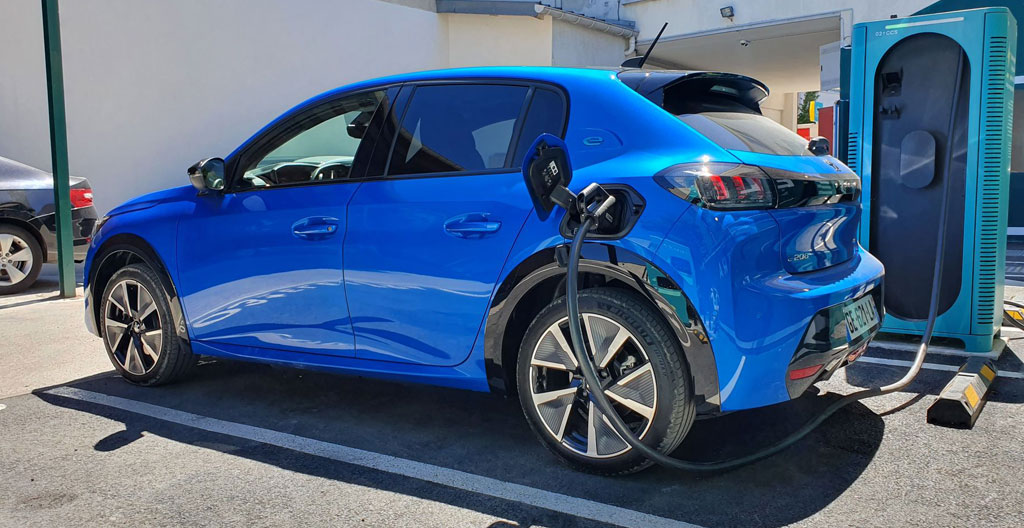 Personne de dos observant une borne de recharge électrique dans un parking urbain
